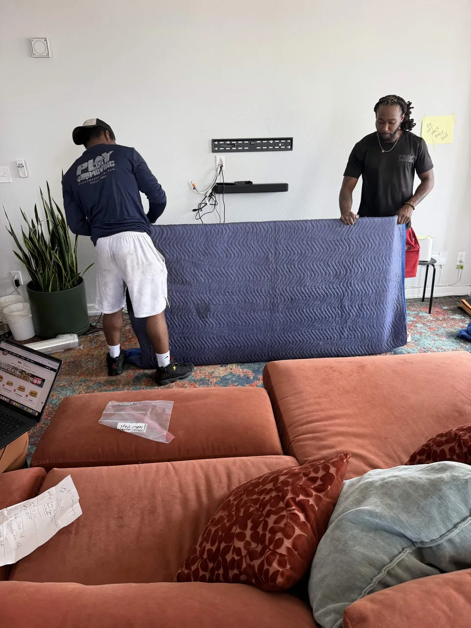 Playhouse Moving crew protecting a large television with a moving blanket