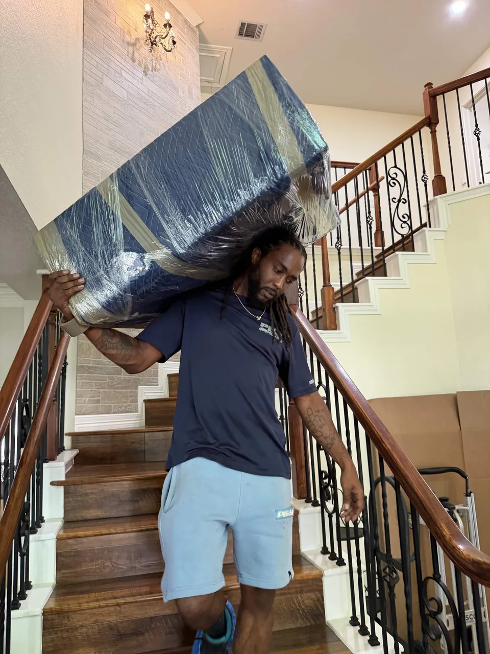 Playhouse Moving crew member carrying padded furniture down a staircase