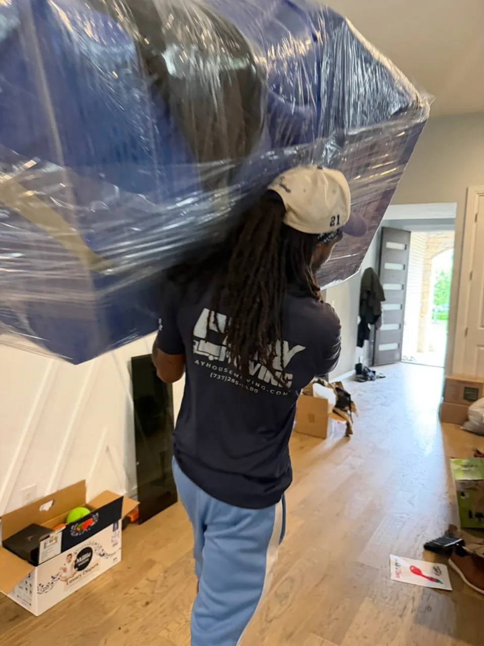 Crew member carrying a large padded and wrapped item through a home